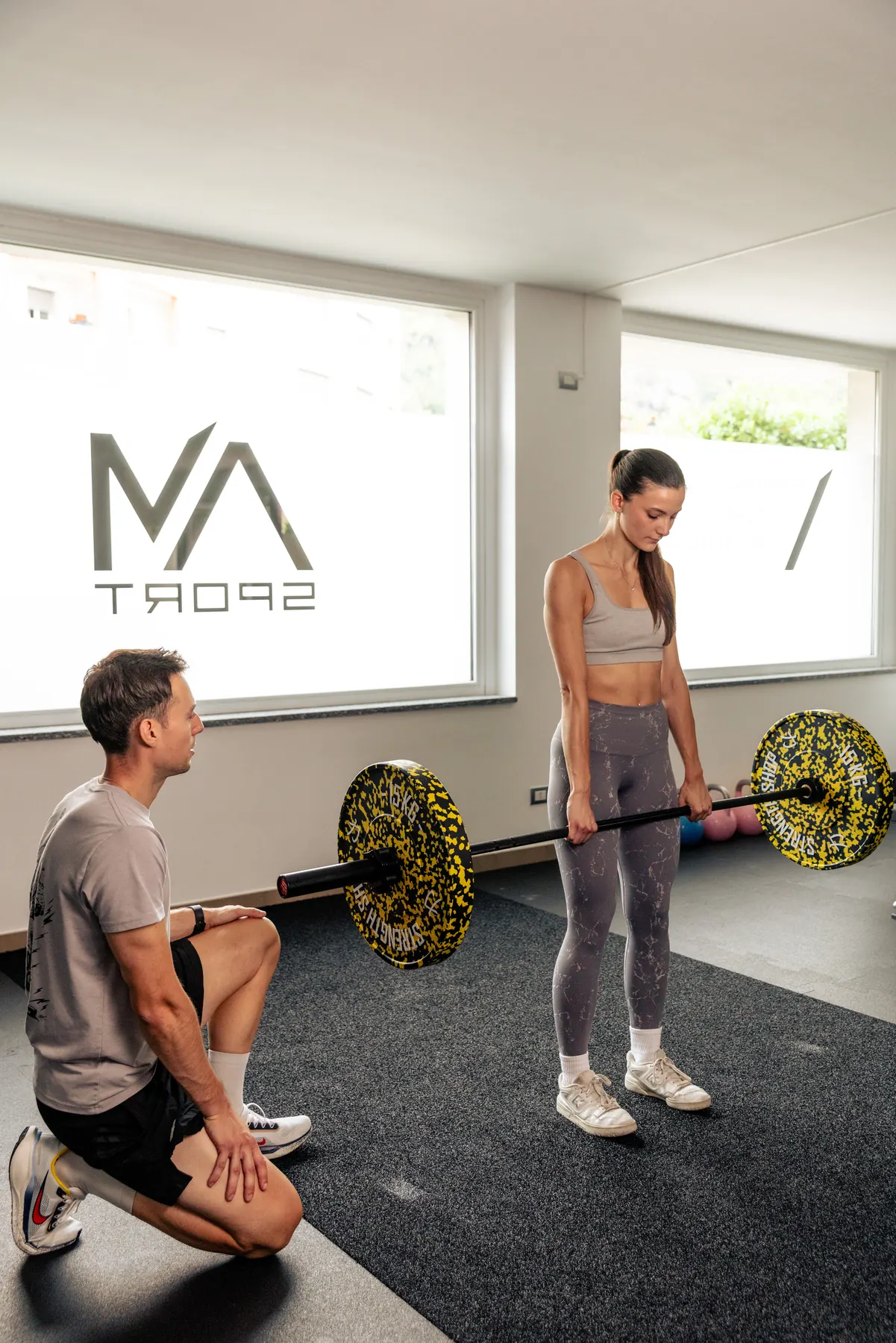 Personal training one-to-one durante un esercizio con bilanciere